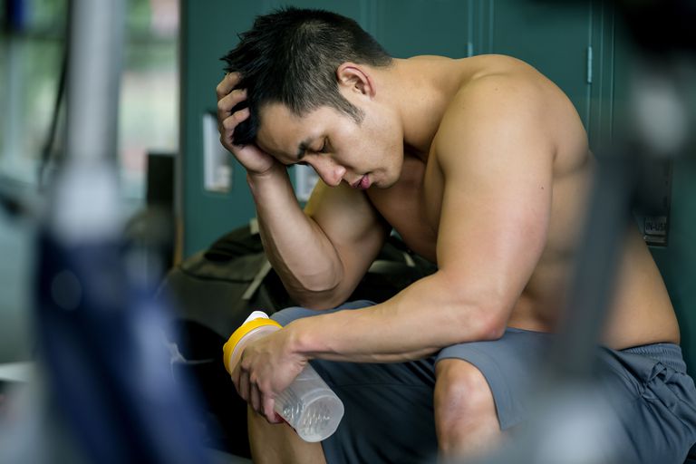 A young fit man with a gym shaker looking sad
