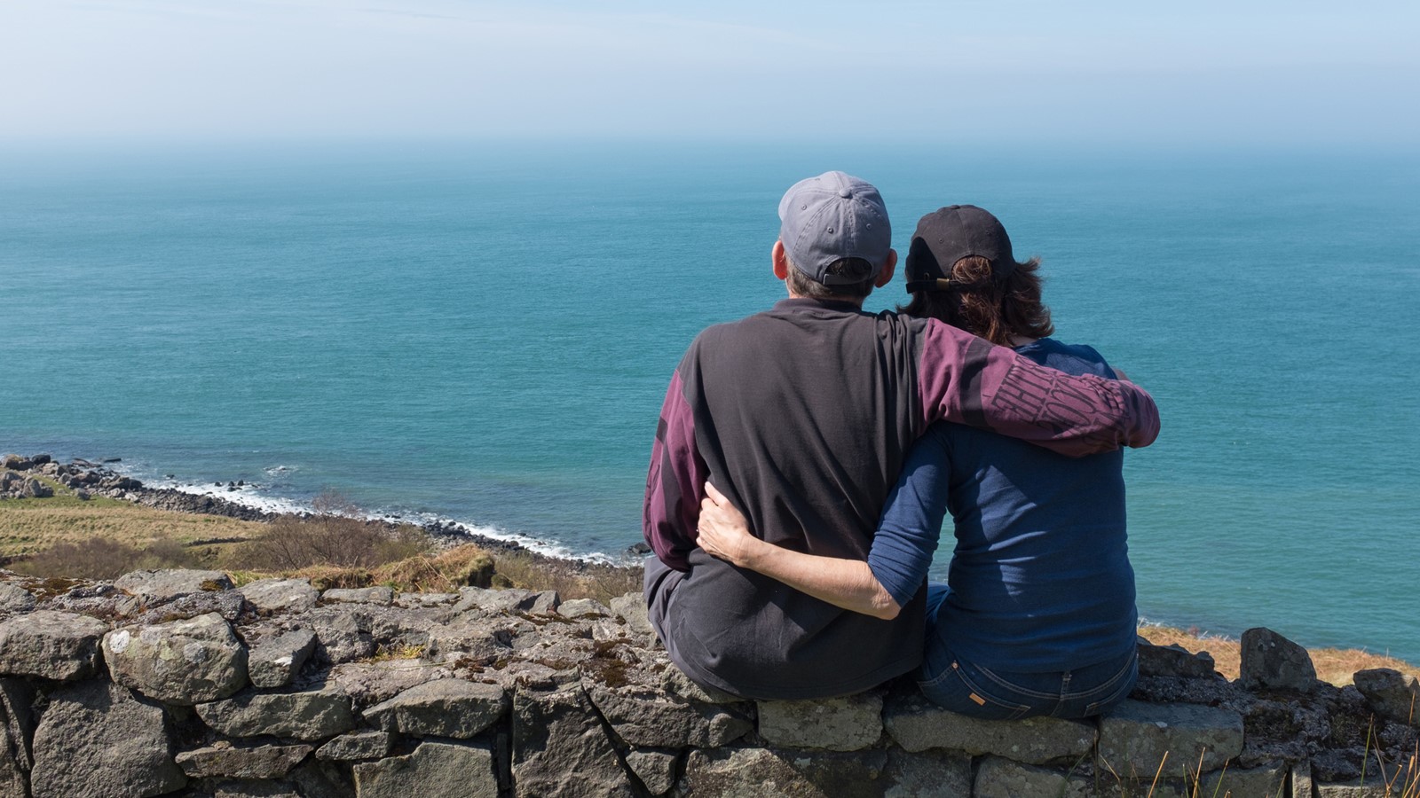 Two people hugging and looking out at the ocean