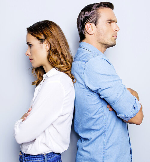 Portrait of unhappy frustrated couple standing back to back not speaking to each other after an argument while standing on grey background. Negative emotion face expression reaction