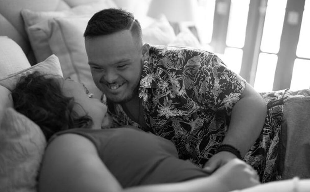 A couple in bed smiling and laughing at each other