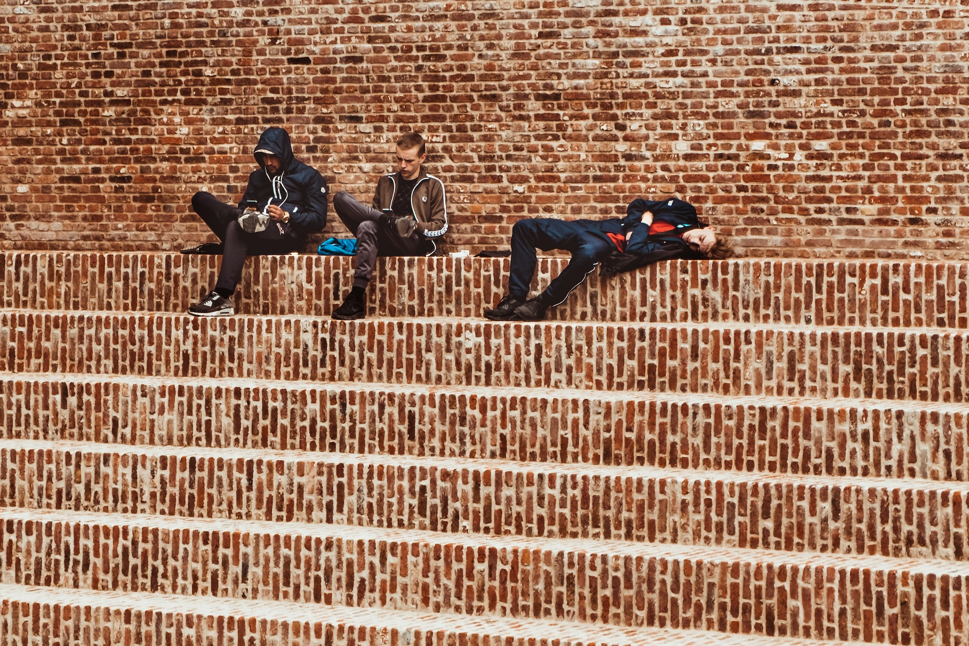 3 men, relaxing and lying down on brick steps