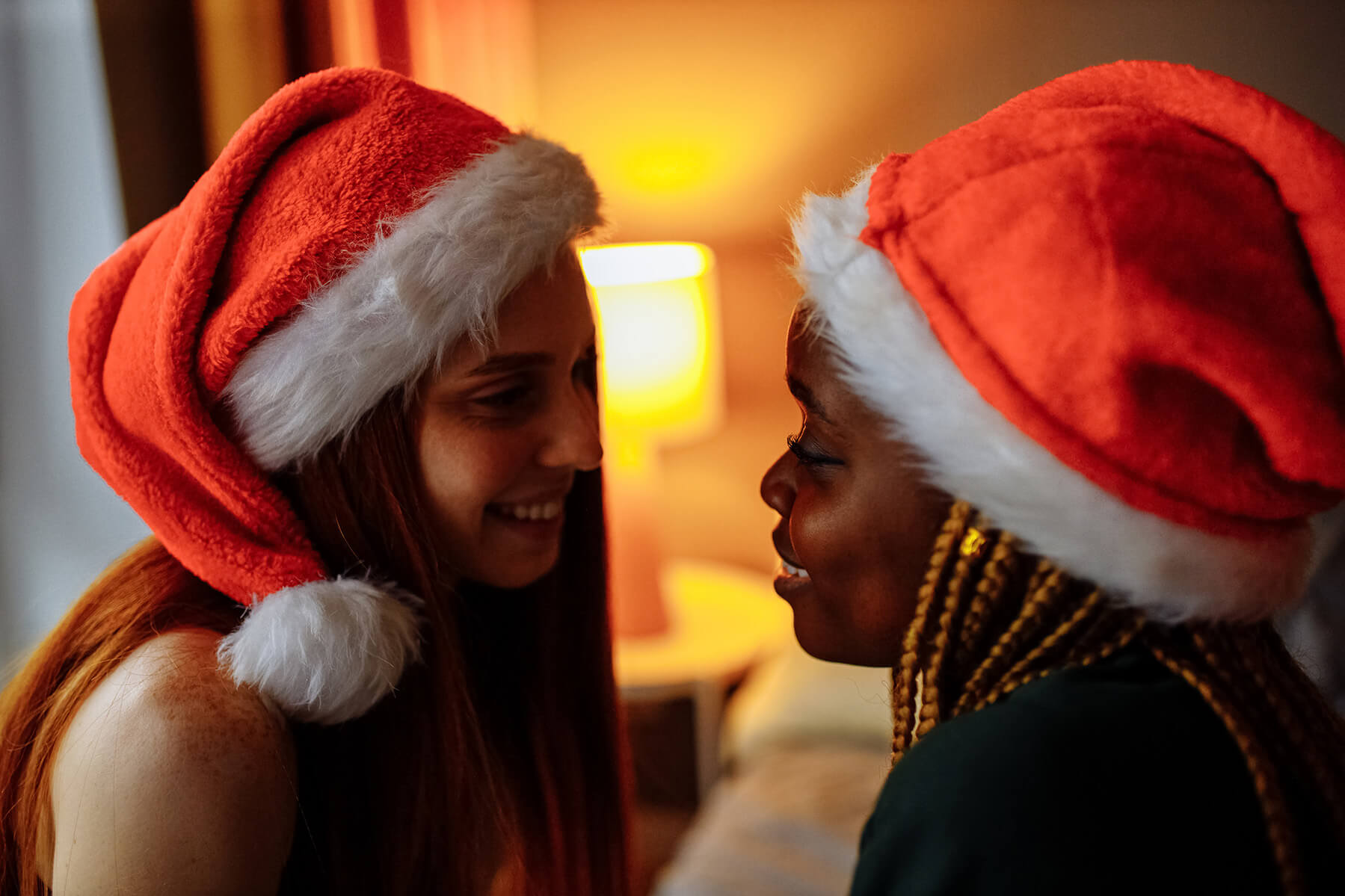 2 women wearing santas hat looking into each others eyes
